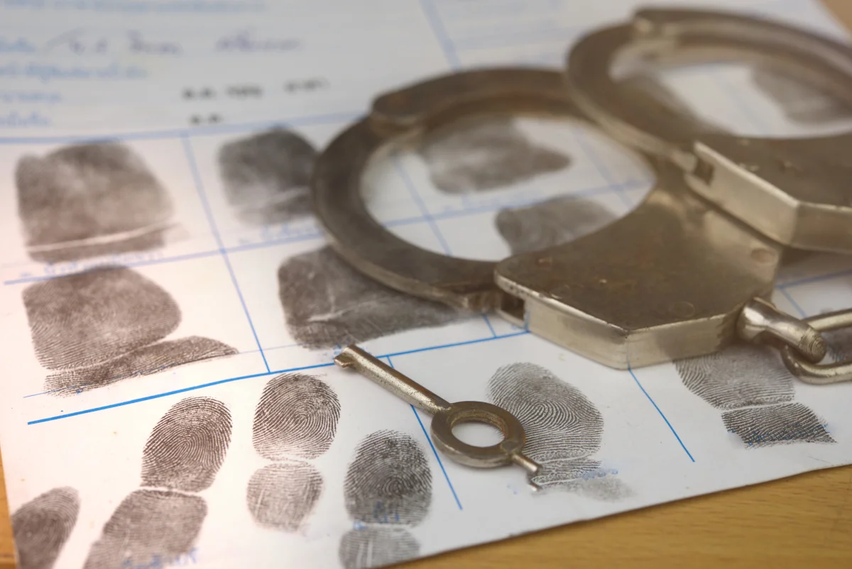 Handcuffs resting on fingerprint sheet.